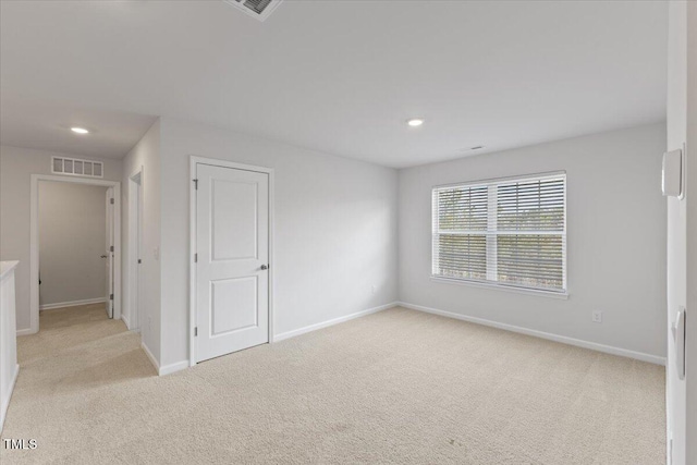 unfurnished room with light carpet, recessed lighting, visible vents, and baseboards