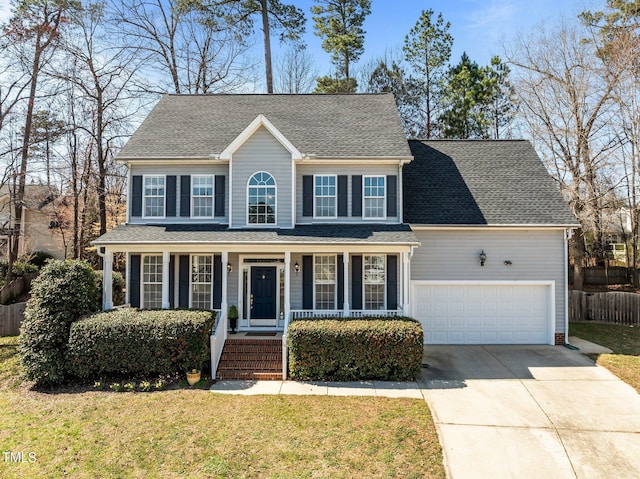 colonial-style house featuring a front lawn, fence, covered porch, concrete driveway, and a garage