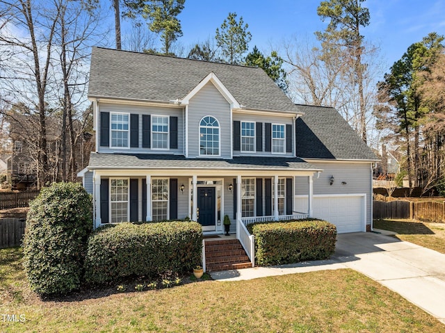 colonial-style house featuring driveway, fence, covered porch, a front yard, and a garage