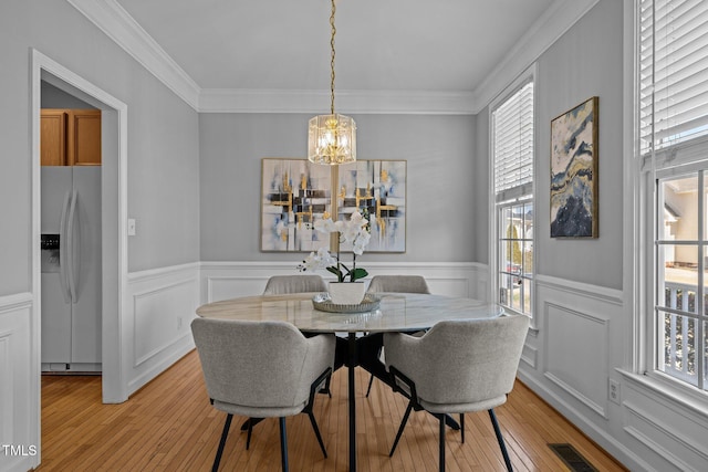 dining area with visible vents, light wood-style floors, an inviting chandelier, and crown molding