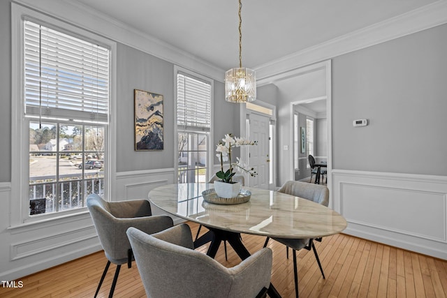 dining space with crown molding, hardwood / wood-style flooring, a notable chandelier, and a decorative wall