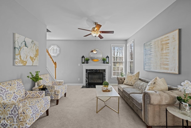 carpeted living area featuring a fireplace, baseboards, stairs, and a ceiling fan