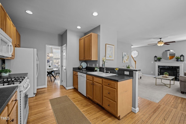 kitchen featuring a sink, dark countertops, open floor plan, white appliances, and a peninsula