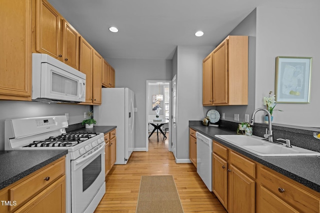 kitchen featuring dark countertops, white appliances, light wood-style floors, and a sink