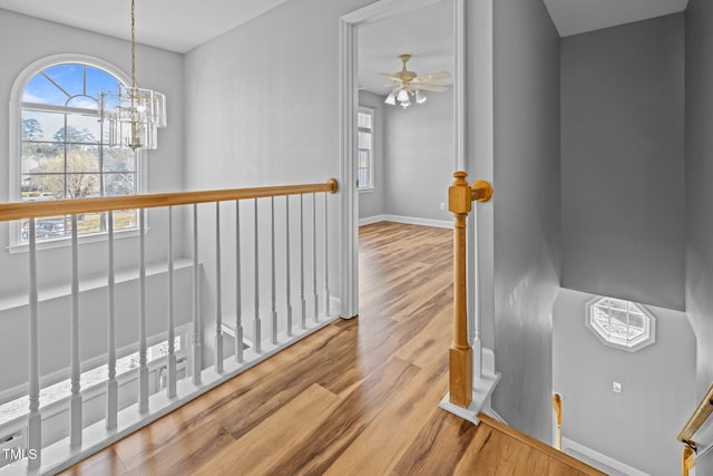 hall featuring an upstairs landing, a notable chandelier, baseboards, and wood finished floors