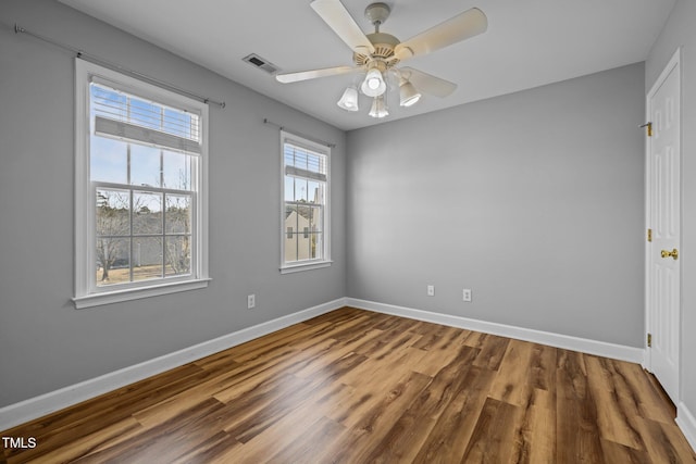 spare room featuring ceiling fan, wood finished floors, visible vents, and baseboards