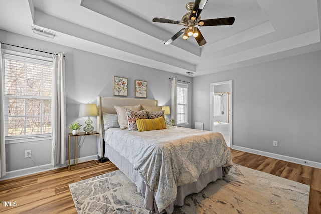 bedroom with a raised ceiling, baseboards, and wood finished floors