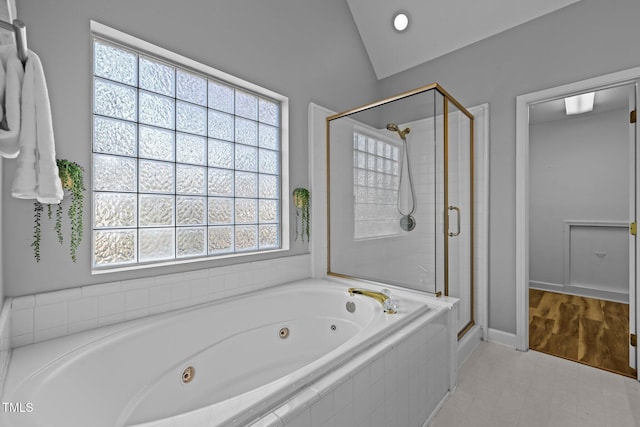 bathroom featuring vaulted ceiling, a jetted tub, and a stall shower