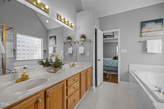 full bathroom with connected bathroom, lofted ceiling, double vanity, a bath, and a sink