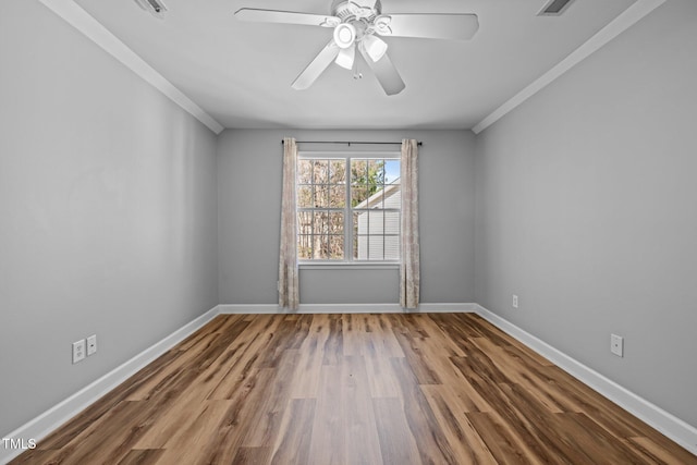 unfurnished room with a ceiling fan, visible vents, wood finished floors, baseboards, and ornamental molding