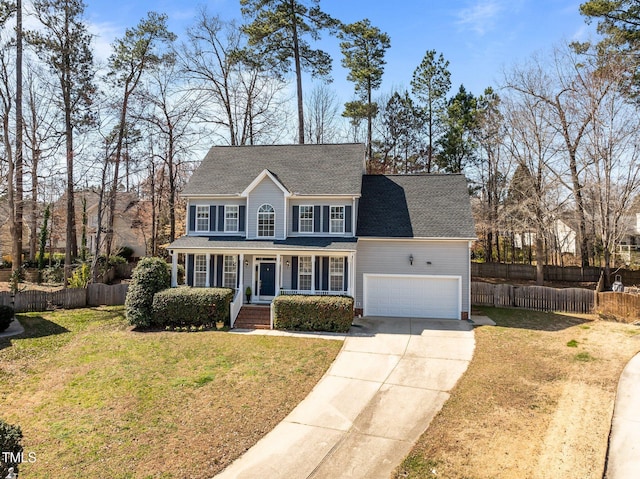 colonial house featuring a front yard, fence, driveway, an attached garage, and a shingled roof