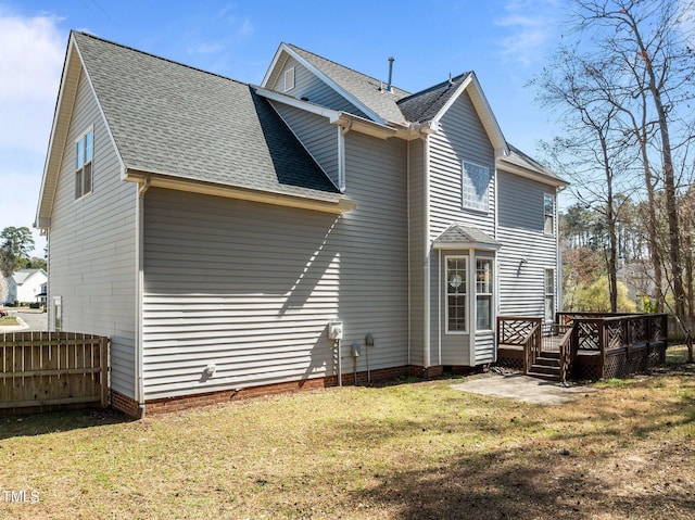 rear view of house featuring a shingled roof, fence, a lawn, a deck, and crawl space