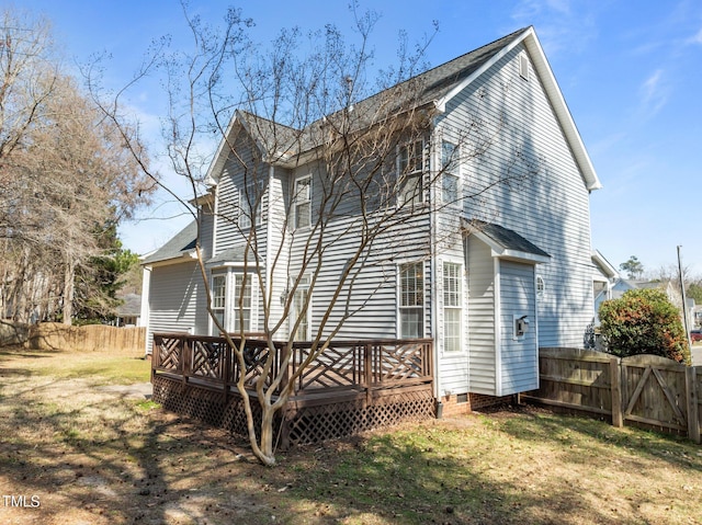 rear view of house with a gate, a wooden deck, a lawn, and fence