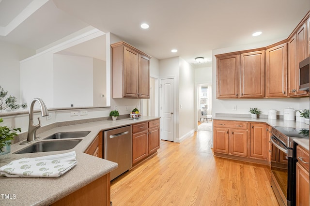 kitchen with appliances with stainless steel finishes, light countertops, light wood-style floors, and a sink