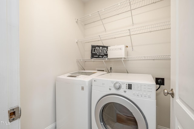 washroom with laundry area, washer and dryer, and baseboards