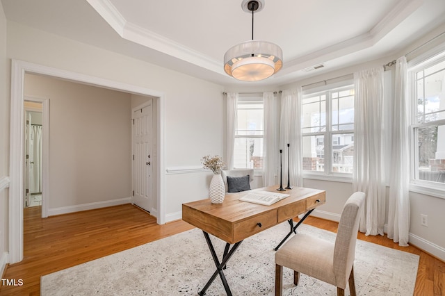 office space with visible vents, plenty of natural light, light wood-style floors, and a tray ceiling