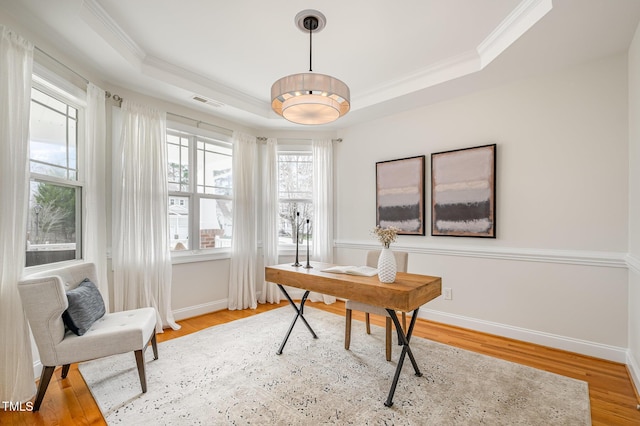 office space featuring a tray ceiling, baseboards, wood finished floors, and ornamental molding