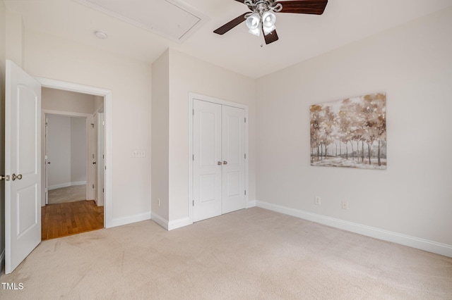 unfurnished bedroom featuring ceiling fan, baseboards, attic access, carpet floors, and a closet