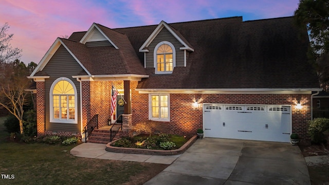 view of front facade with brick siding, a shingled roof, a yard, a garage, and driveway