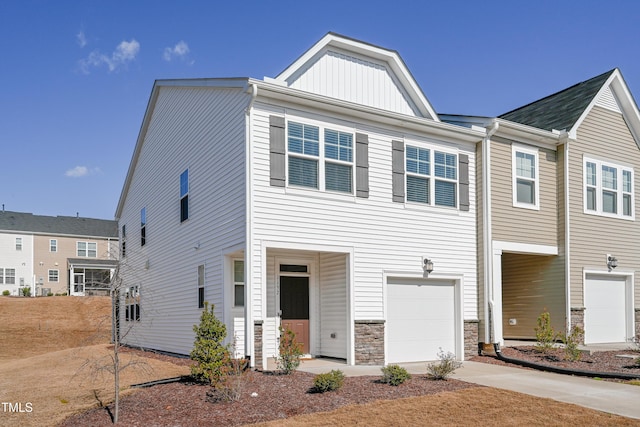 multi unit property featuring stone siding, board and batten siding, an attached garage, and driveway