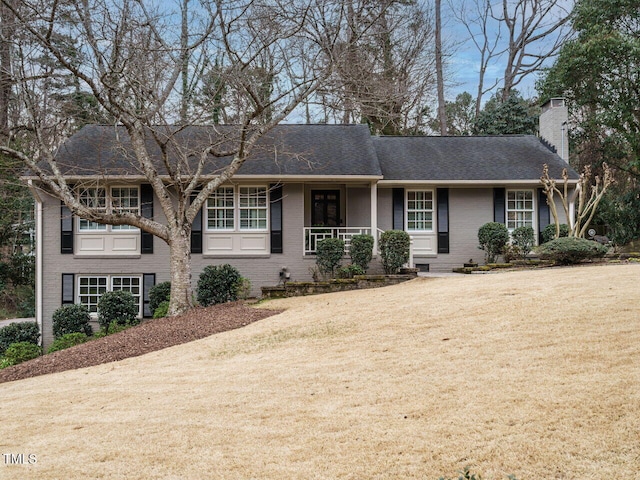 single story home featuring brick siding, a chimney, and a front yard