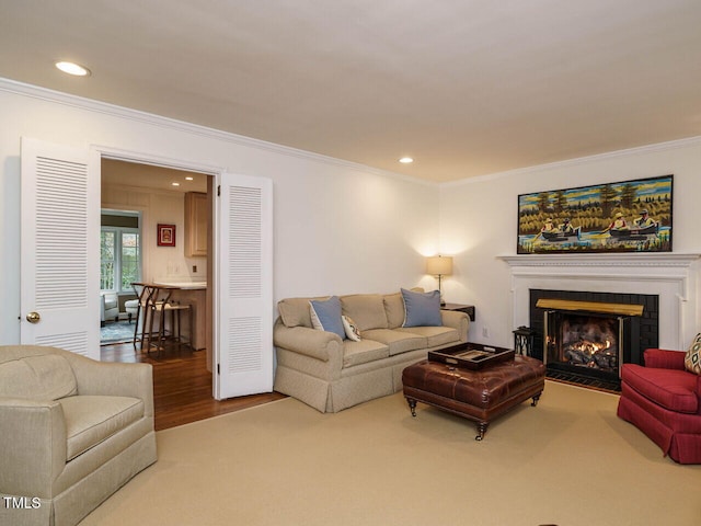 living room with recessed lighting, wood finished floors, a lit fireplace, and ornamental molding