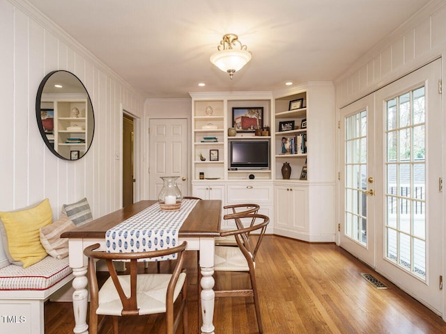 dining space featuring light wood finished floors, visible vents, french doors, and crown molding