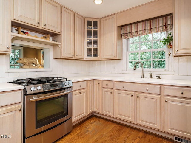 kitchen featuring visible vents, stainless steel range with gas stovetop, a sink, light countertops, and backsplash