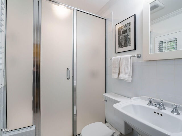 bathroom with toilet, a stall shower, tile walls, and a sink