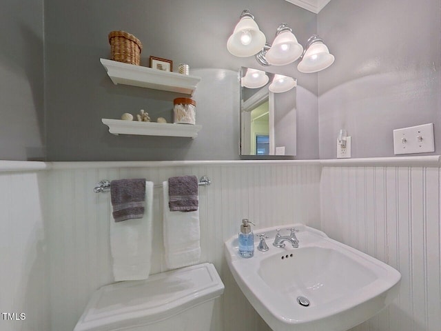 bathroom with a sink, toilet, and wainscoting