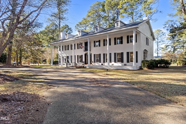 greek revival inspired property with a porch, stucco siding, a front lawn, and aphalt driveway