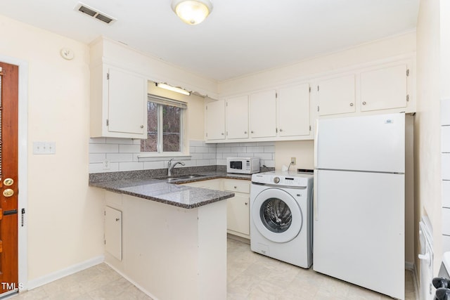 kitchen with a sink, washer / clothes dryer, tasteful backsplash, white appliances, and a peninsula