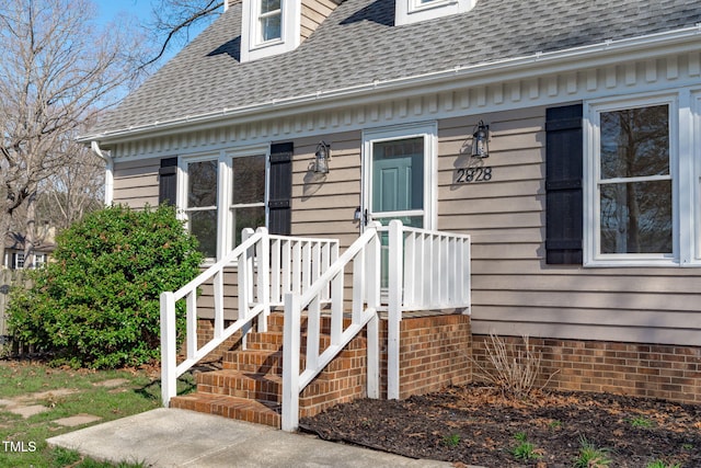 entrance to property featuring roof with shingles