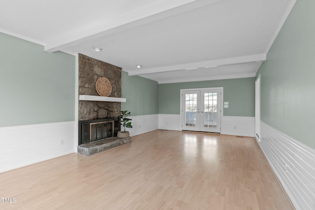 unfurnished living room with beamed ceiling, french doors, and a wainscoted wall