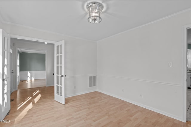 unfurnished room with crown molding, light wood-style flooring, french doors, and visible vents