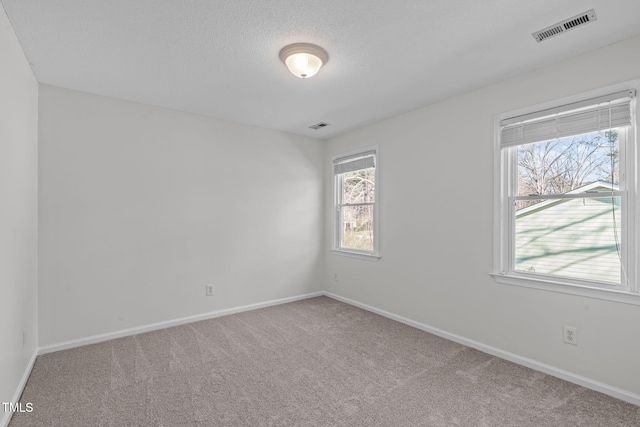 empty room with visible vents, carpet flooring, a textured ceiling, and baseboards