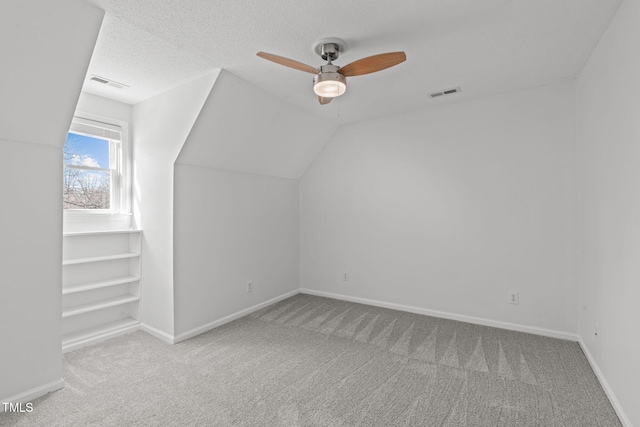 bonus room with visible vents, carpet flooring, a textured ceiling, and lofted ceiling