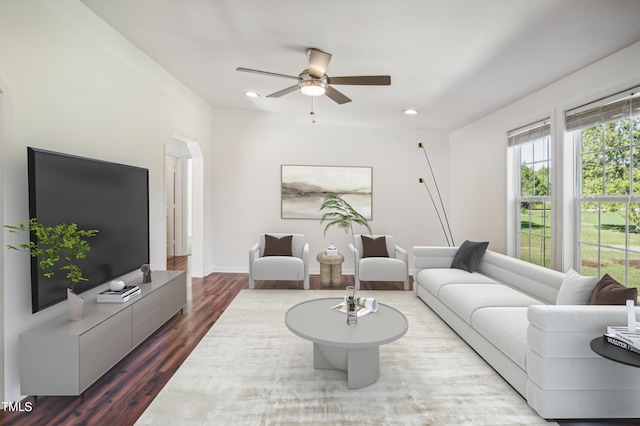 living room featuring baseboards, arched walkways, a ceiling fan, dark wood-style floors, and recessed lighting