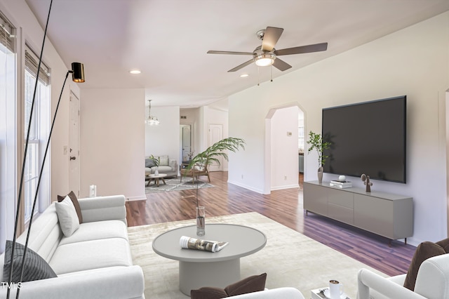 living area with arched walkways, recessed lighting, ceiling fan with notable chandelier, wood finished floors, and baseboards