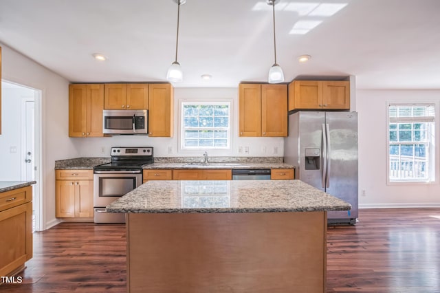 kitchen with stainless steel appliances, plenty of natural light, dark wood finished floors, and a center island