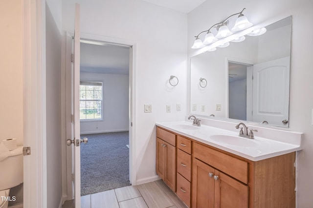 bathroom with double vanity, baseboards, and a sink