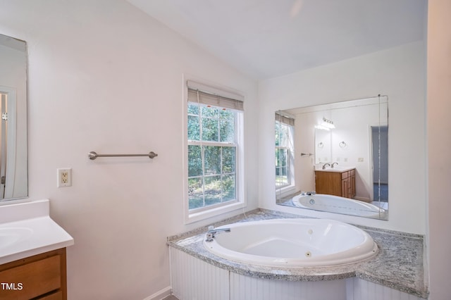 full bath with two vanities, a sink, and a jetted tub