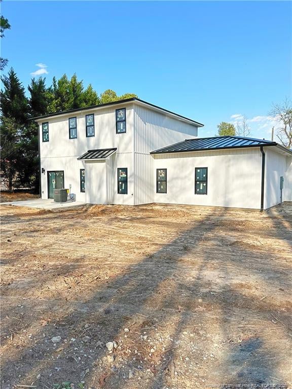 view of front of house featuring a standing seam roof, metal roof, and cooling unit