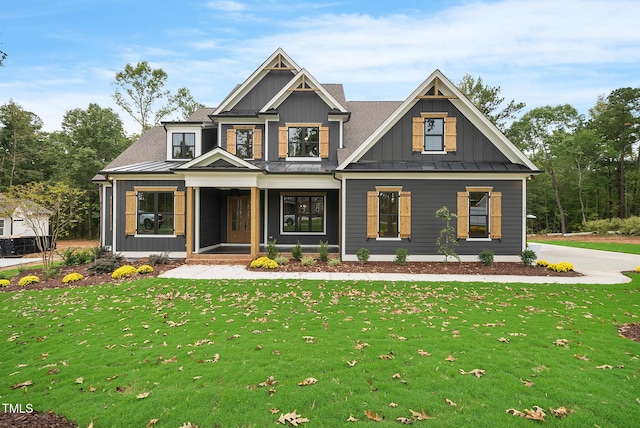 view of front facade featuring board and batten siding, a front yard, covered porch, metal roof, and a standing seam roof