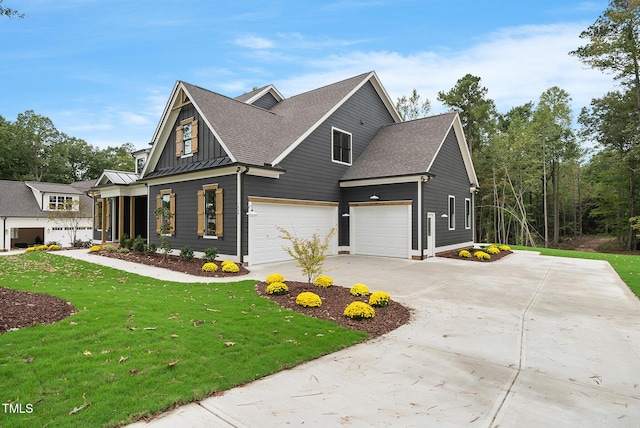 view of front of house featuring a shingled roof, a front yard, driveway, an attached garage, and a standing seam roof