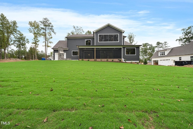 rear view of house with a yard, a garage, and a sunroom