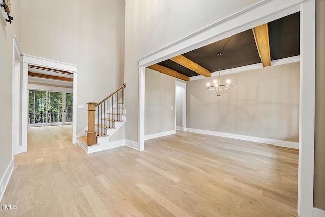 foyer with wood finished floors, baseboards, stairs, beamed ceiling, and a chandelier