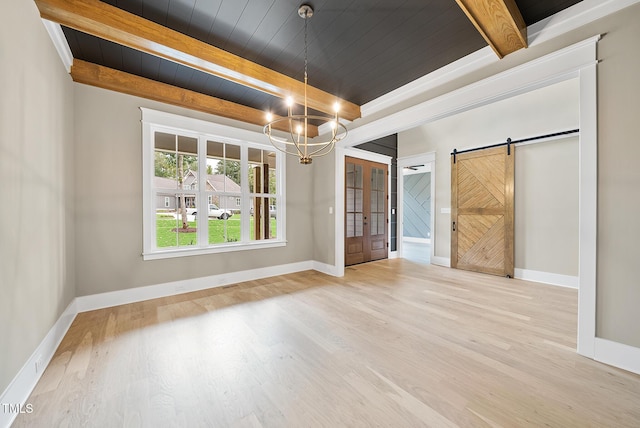 empty room with a barn door, beamed ceiling, wood ceiling, and light wood finished floors