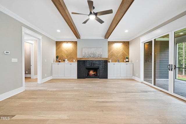 unfurnished living room featuring beamed ceiling, light wood-style flooring, a fireplace, and an accent wall