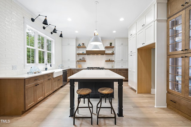 kitchen featuring open shelves, light wood-style flooring, a sink, dishwasher, and backsplash